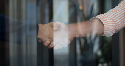 Two people shaking hands in front of a glass door.