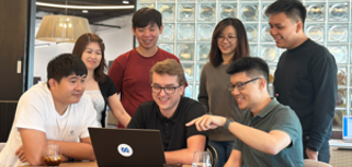 A group of people sitting around a table with a laptop.