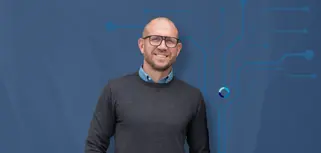 Johan Holmsten z Monitor ERP na niebieskim tle nawiązującym do cyklu życia systemu ERP.