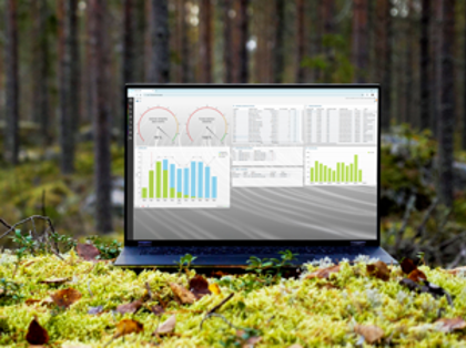 A laptop computer displaying Monitor ERP sitting on top of a moss covered ground surrounded by trees.