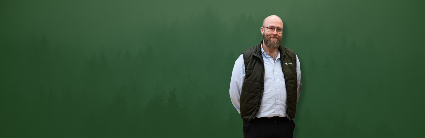 David Mariasdotter, Sustainability consultant at Monitor ERP, standing with hands behind back in front of green background