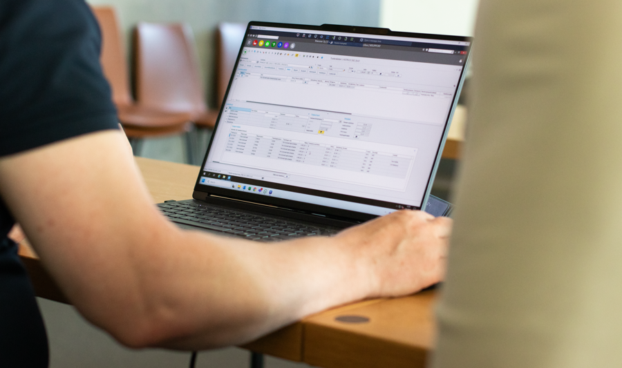 Eine Person, die mit einem Laptop an einem Tisch sitzt und Monitor ERP nutzt.