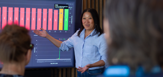A woman at Monitor ERP giving a presentation to a group of people about Monitor BI (business intelligence)