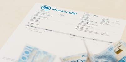 A pile of money sitting on top of an invoice from Monitor ERP.