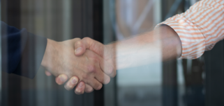 Two people shaking hands in front of a glass door.