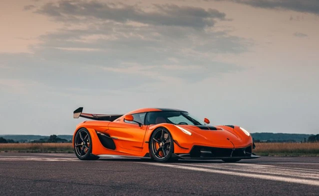 A bright orange sports car is parked on the road.