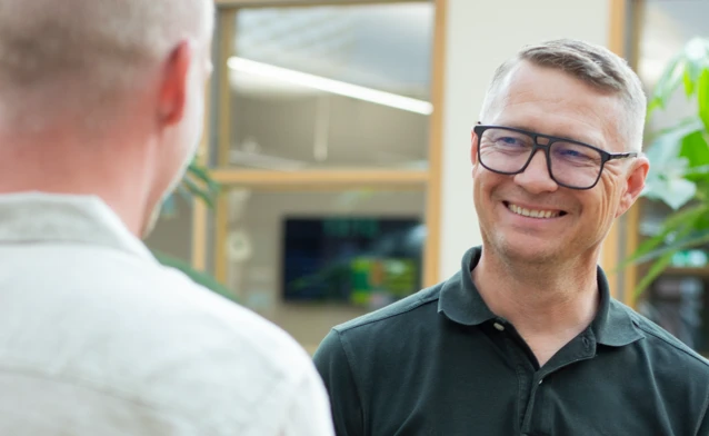 A man standing next to another man at a table looking happy at Monitor ERP HQ.