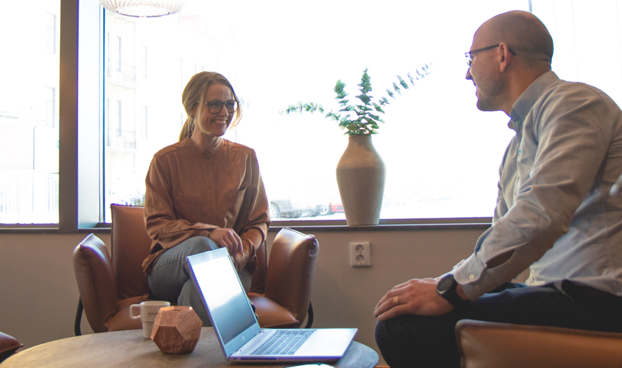 A couple of people sitting in a room with a laptop.