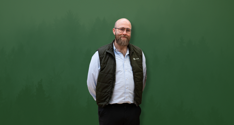 David Mariasdotter, Sustainability consultant at Monitor ERP, standing with hands behind back in front of green background