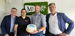 A group of men standing next to each other holding a cake.