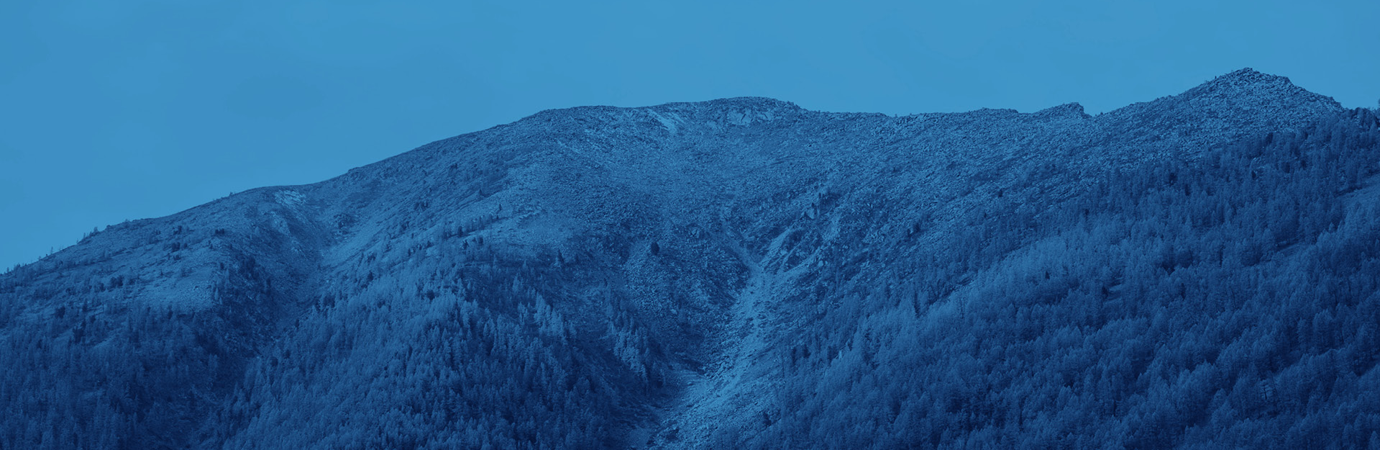 Ett mycket högt, snötäckt berg under en blå himmel.