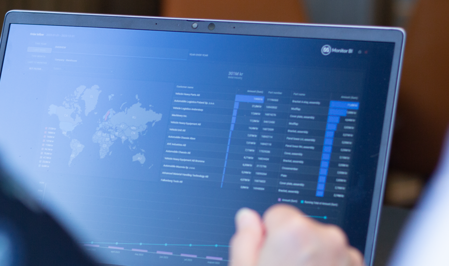 A person sitting in front of a laptop computer with Monitor BI (business intelligence) dashboards. 