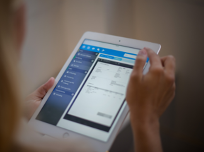 A woman is holding a tablet displaying a digital invoice. 