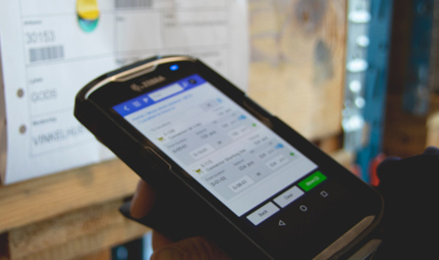 Person in a warehouse scanning pallet labels using a handheld scanner. 