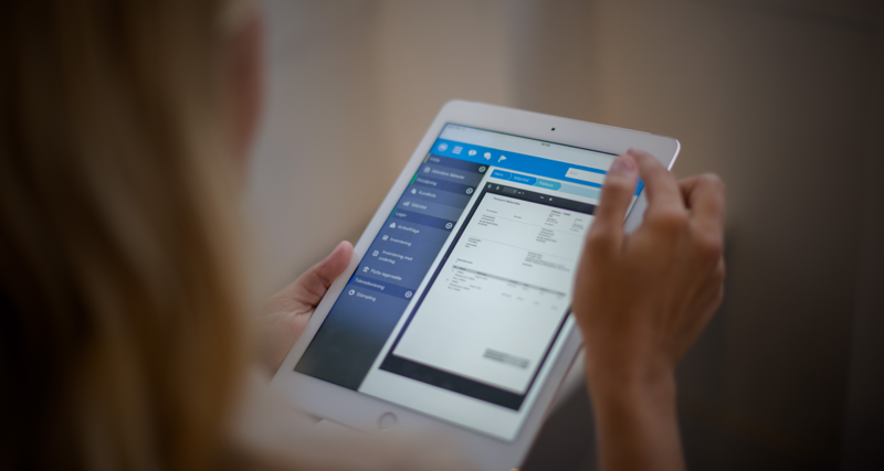 A woman is holding a tablet displaying a digital invoice. 