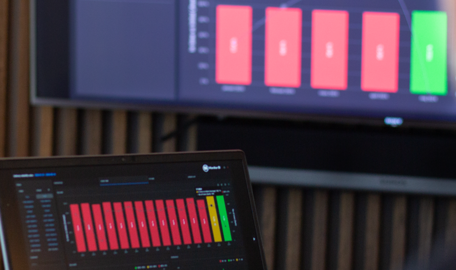 laptop on a table and a screen on a wall, showing Monitor ERP Dashboard