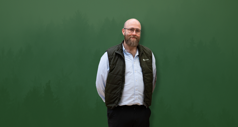David Mariasdotter, Sustainability consultant at Monitor ERP, standing with hands behind back in front of green background