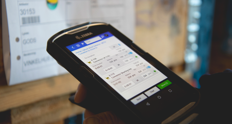 Person in a warehouse scanning pallet labels using a handheld scanner. 