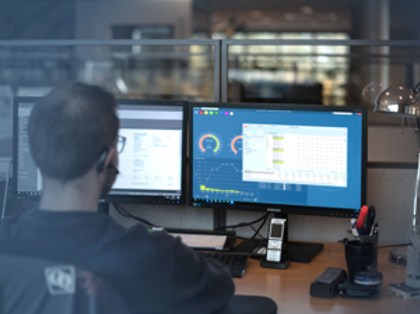 En man sitter framför en dator i en industrimiljö och använder Monitor ERP affärssystem. 