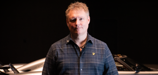 Mikael Melander, Senior ERP System Specialist at Koenigsegg Automotive standing in front of a Koenigsegg sports car.