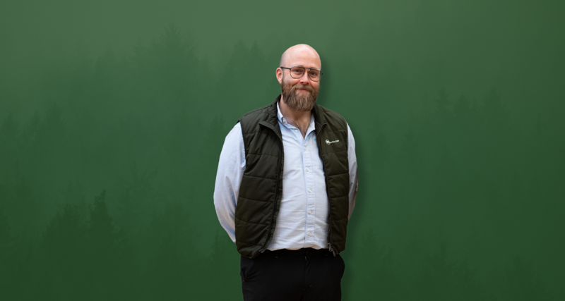 David Mariasdotter, Sustainability consultant at Monitor ERP, standing with hands behind back in front of green background