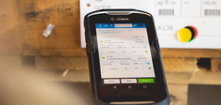 Person in a warehouse scanning pallet labels using a handheld scanner. 