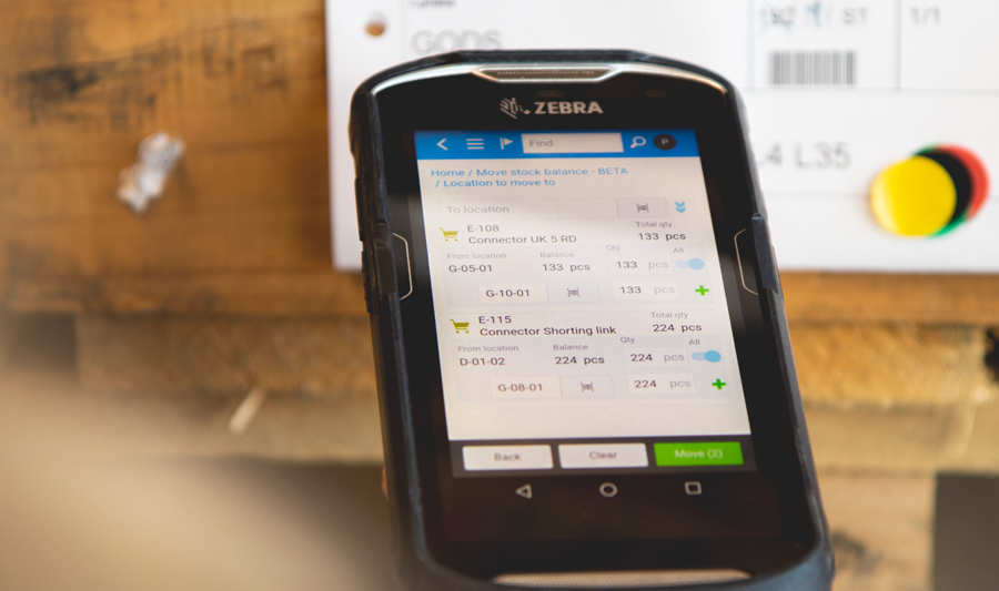 Person in a warehouse scanning pallet labels using a handheld scanner. 