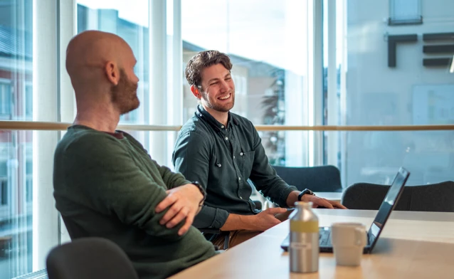 A couple of men sitting at a table with laptops.