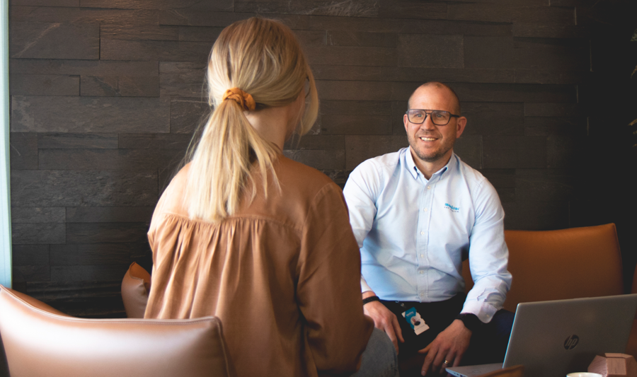 A man and a woman sitting at a table with a laptop.