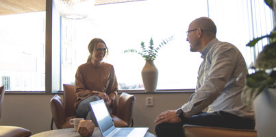 A couple of people sitting in a room with a laptop.