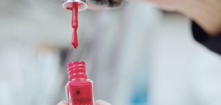 A woman is holding a bottle of nail polish.