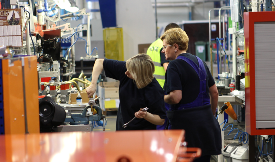A group of people standing in a facturing environment. 