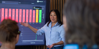 A woman at Monitor ERP giving a presentation to a group of people about Monitor BI (business intelligence)