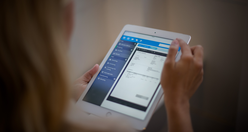 A woman is holding a tablet displaying a digital invoice. 