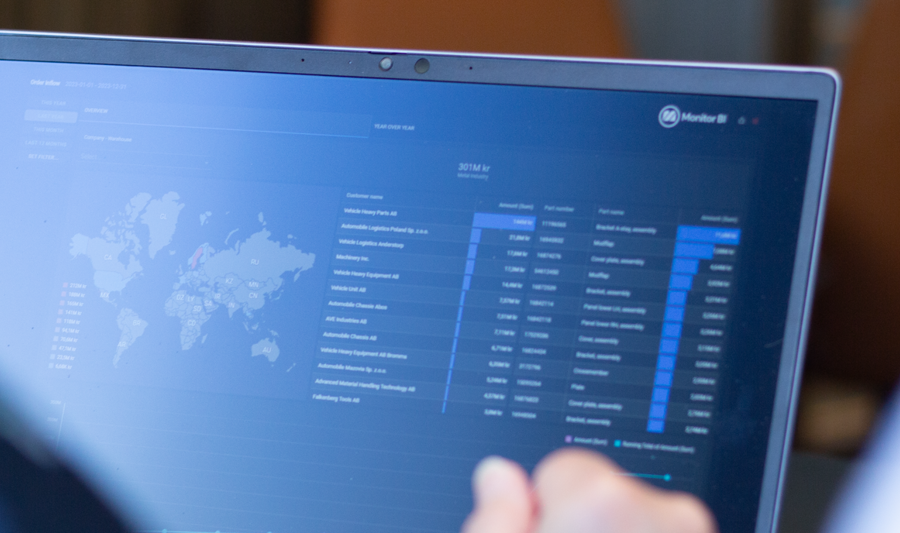 A person sitting in front of a laptop computer with Monitor BI (business intelligence) dashboards. 