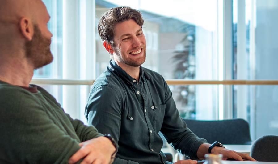 A couple of men sitting at a table with laptops.