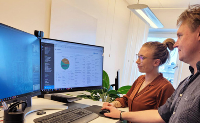 Dwoje ludzi przy komputerze - jedna z osób wyjaśnia drugiej jak działa system Monitor ERP.
