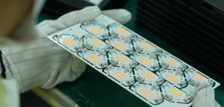 A person in white gloves holding a box of pills.