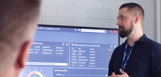 A man standing in front of a large screen displaying the ERP system Monitor ERP. 