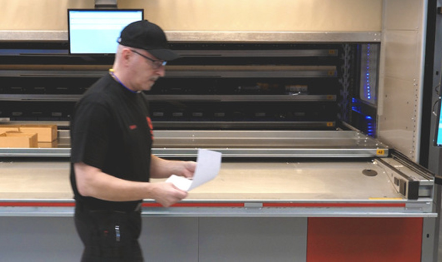 A man in a black shirt is walking by a machine.