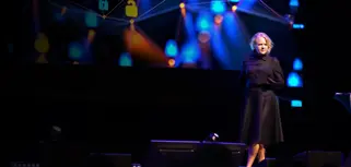A woman standing on a stage in front of a crowd.