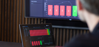 laptop on a table and a screen on a wall, showing Monitor ERP Dashboard