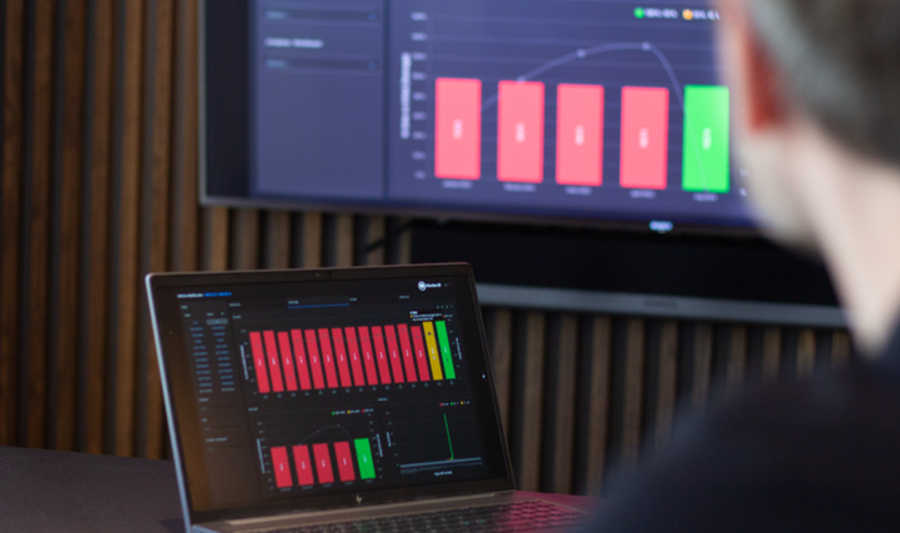 laptop on a table and a screen on a wall, showing Monitor ERP Dashboard
