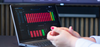 A person sitting in front of a laptop computer with Monitor BI (business intelligence) dashboards. 