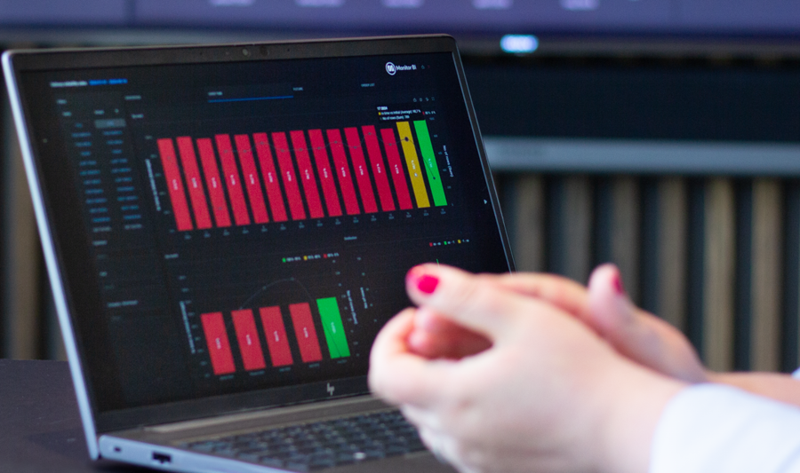 A person sitting in front of a laptop computer with Monitor BI (business intelligence) dashboards. 