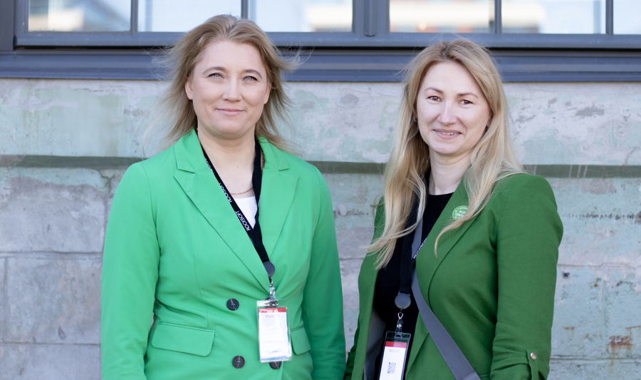Two women standing next to each other dressed in green