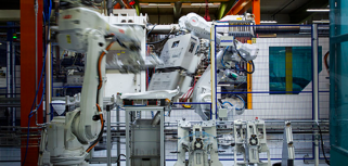 En stor maskin i en byggnad med en lyftkran i bakgrunden.