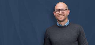 Johan Holmsten, global sales manager at Monitor ERP, standing infront of a blue background