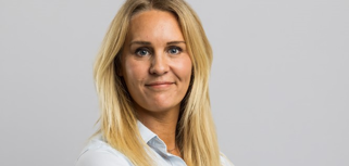 Jenny Tiedman, ansvarig för redovisning och logistik på Skotte står bakom en grå bakgrund.
