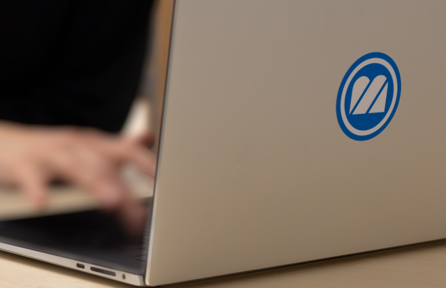 A person typing on a laptop with a pen.
